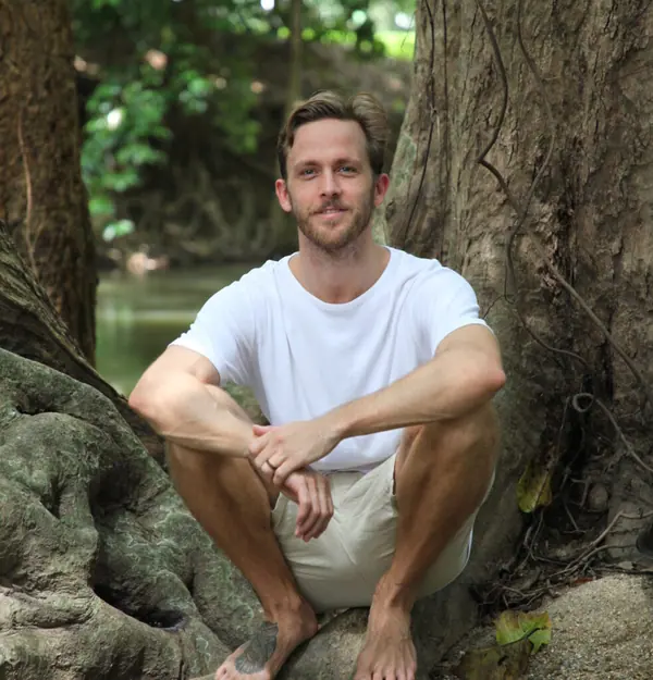 Campbell Will sitting against large tree roots near water